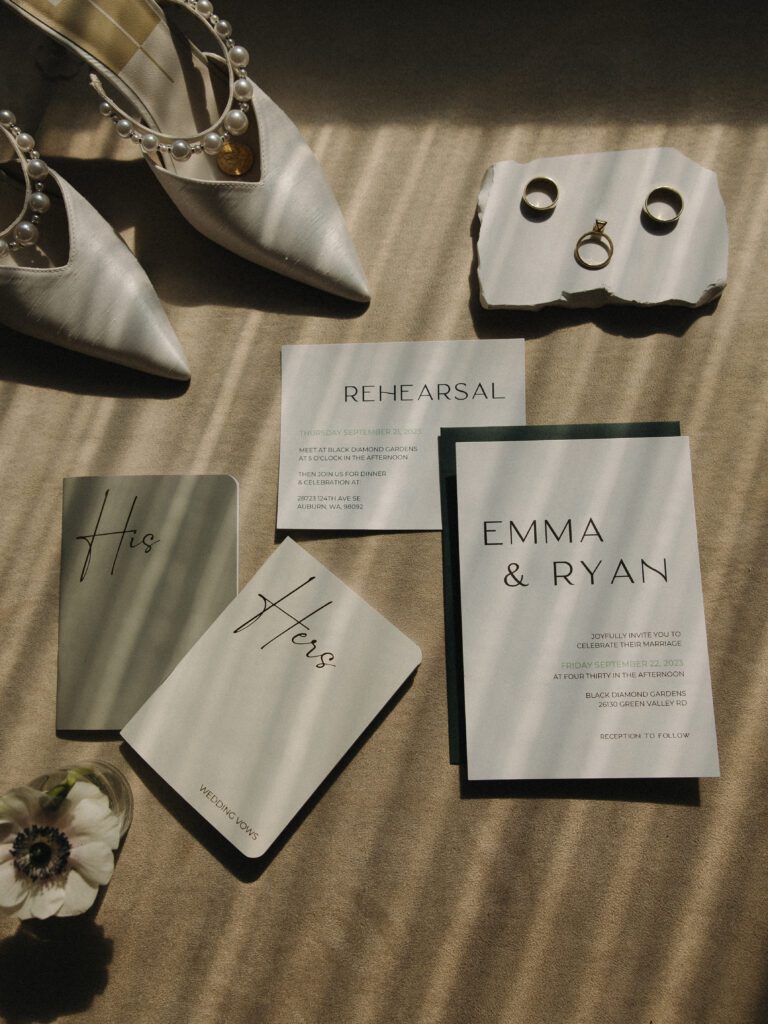 a flat lay detail including rings, wedding invitations, shoes and vow books