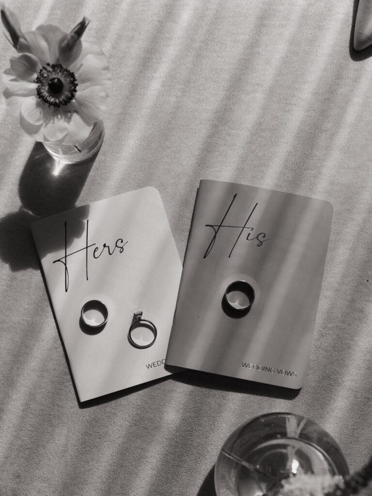 black and white photo of vow books with wedding rings on top